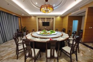 Una mesa de comedor redonda con sillas, una araña y una pantalla de televisión en la pared.