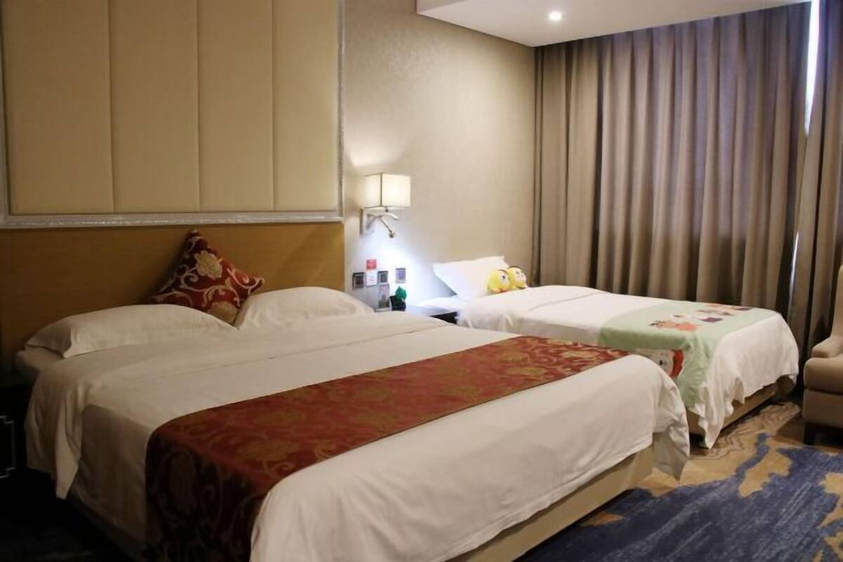 Una habitación de hotel con dos camas, una mesita de noche, una lámpara y una silla.