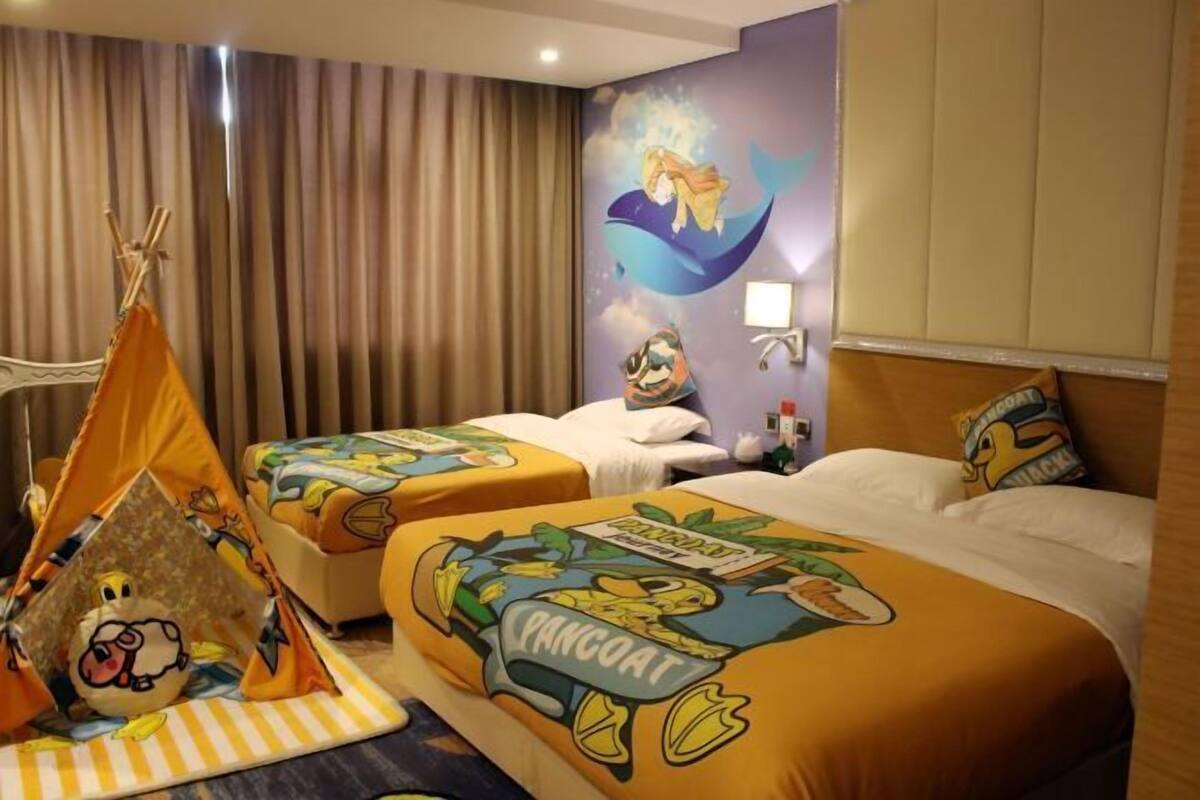 Habitación de hotel con dos camas, una tienda tipi y un mural de una sirena.