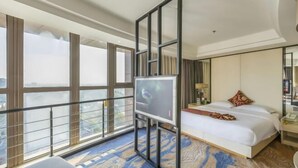 Una camera d'albergo con una grande finestra, un letto, una TV e un comodino.