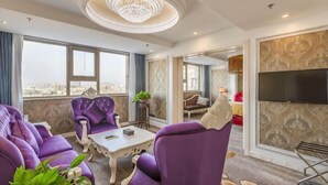 Un soggiorno moderno con mobili viola, un lampadario, un televisore a schermo piatto e ampie finestre.