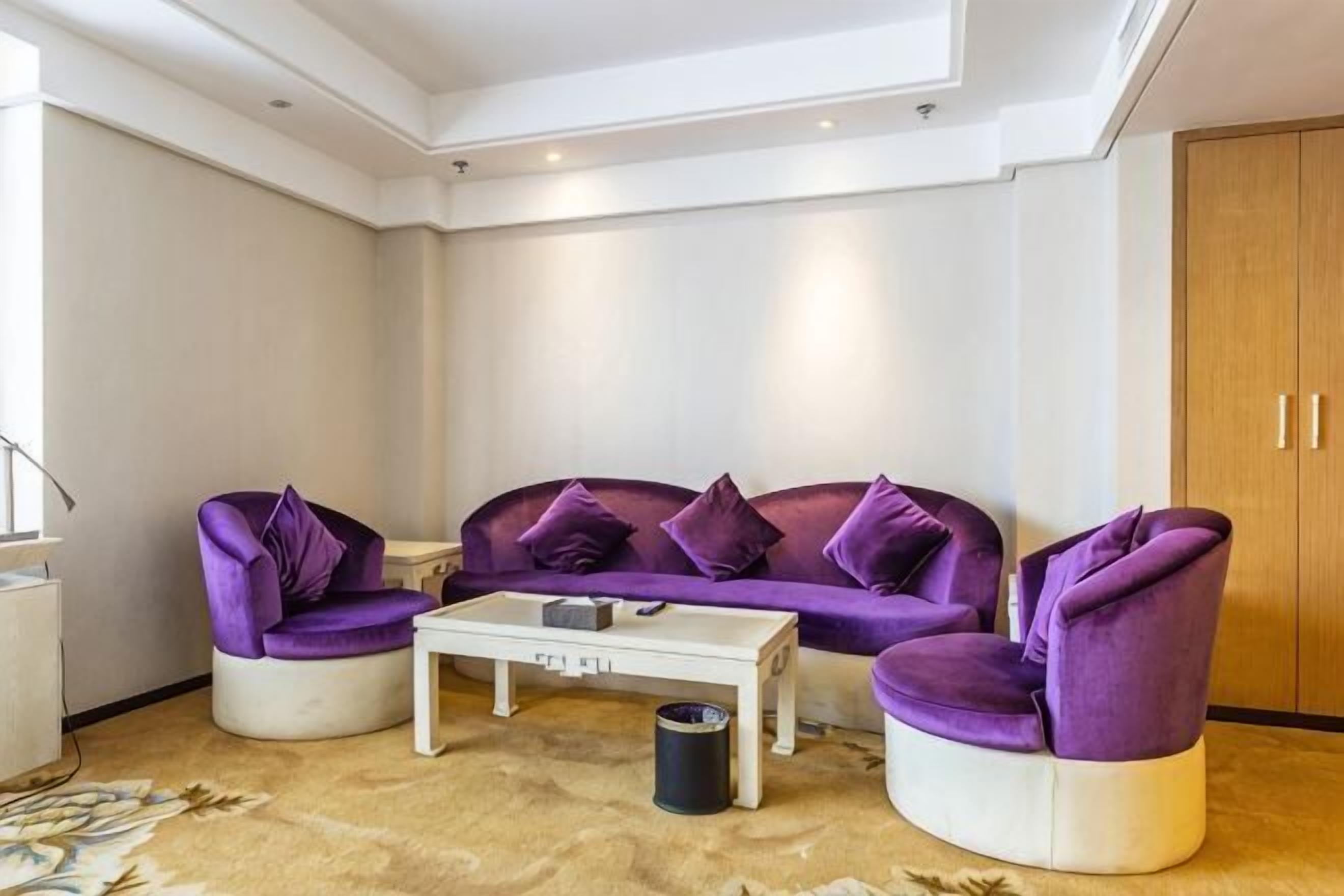 A living room with a purple sofa set, a white coffee table, and a wooden cabinet.