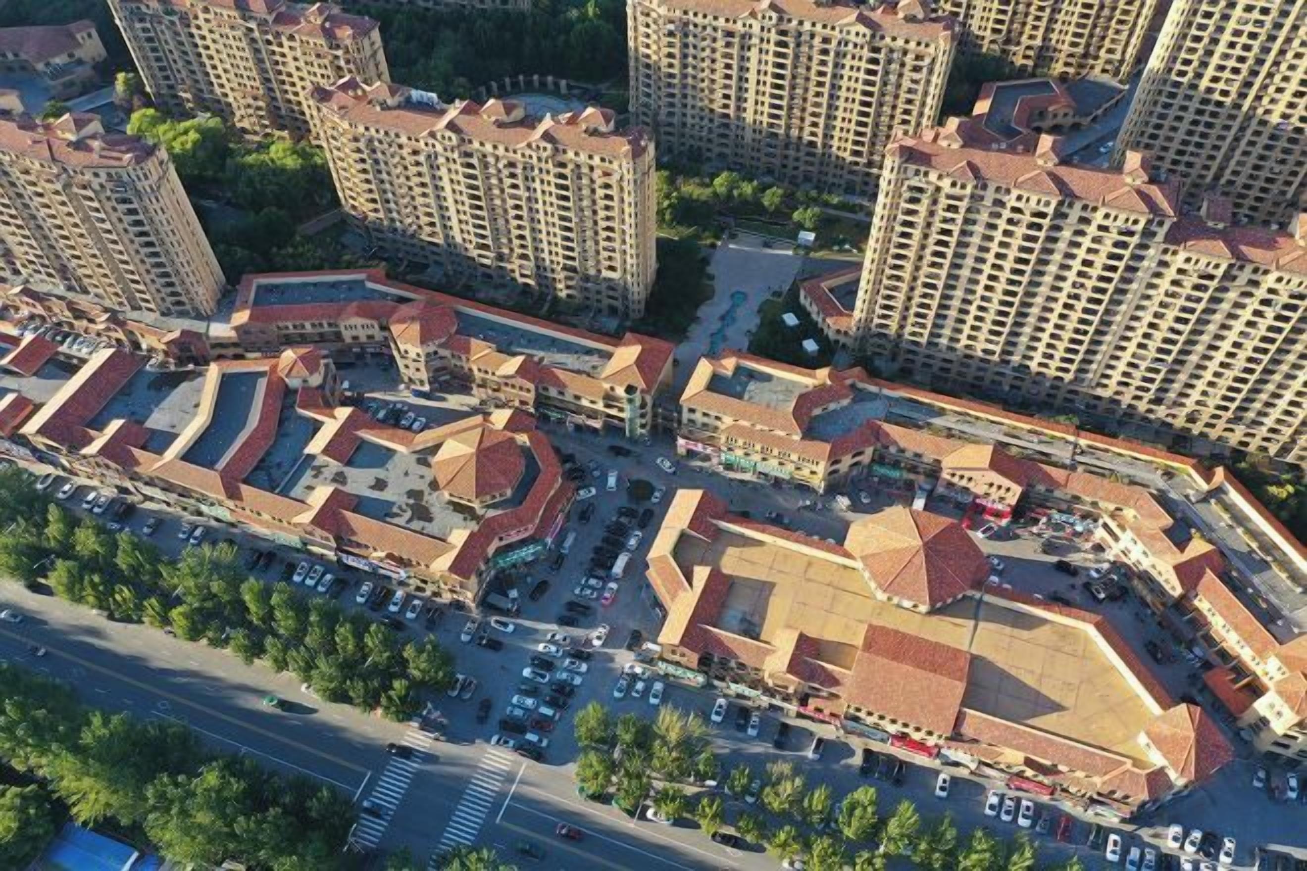 Un complejo residencial de edificios altos, con varios edificios de apartamentos, un patio central y un área de estacionamiento.