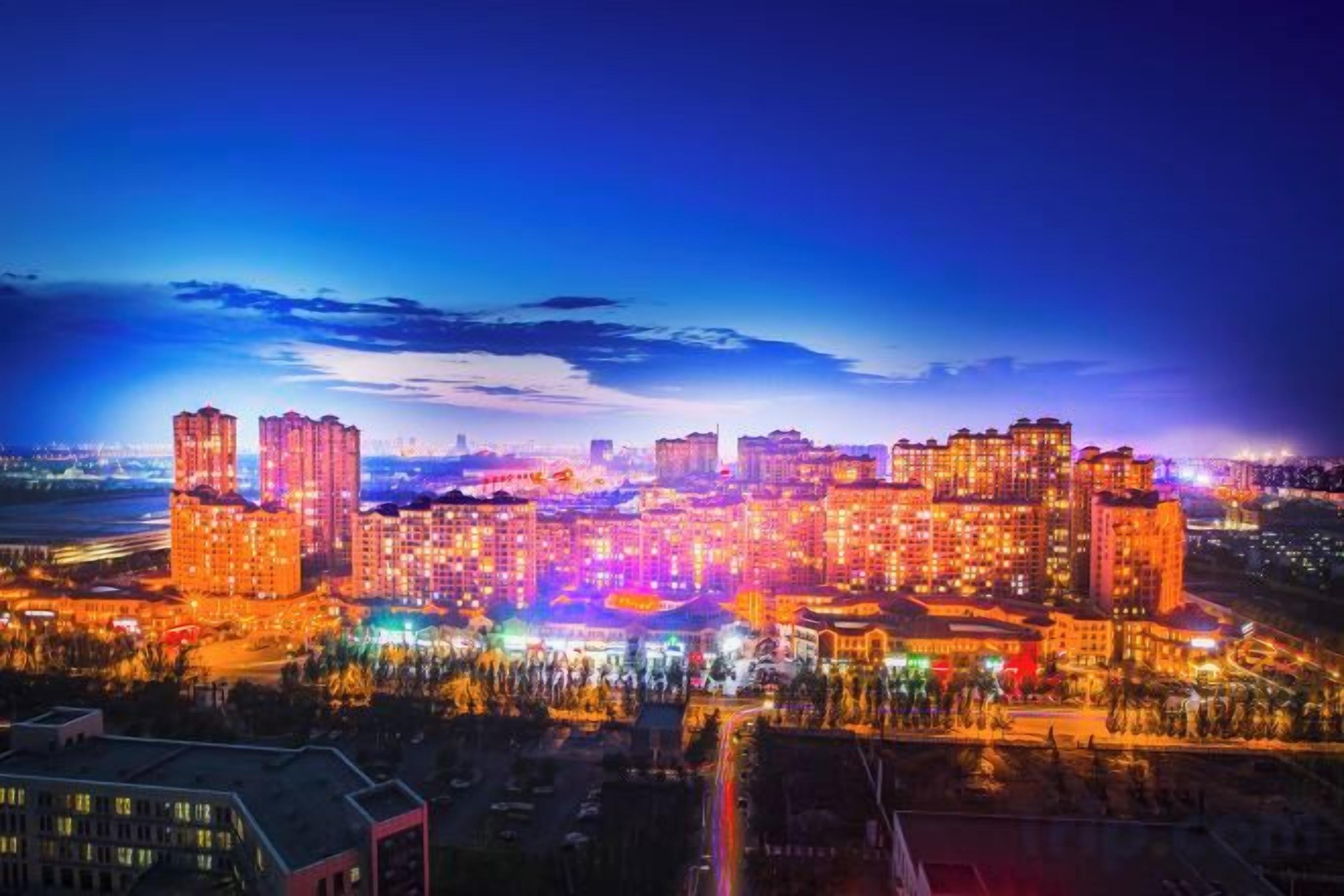 A cityscape at night with illuminated buildings and a clear sky.