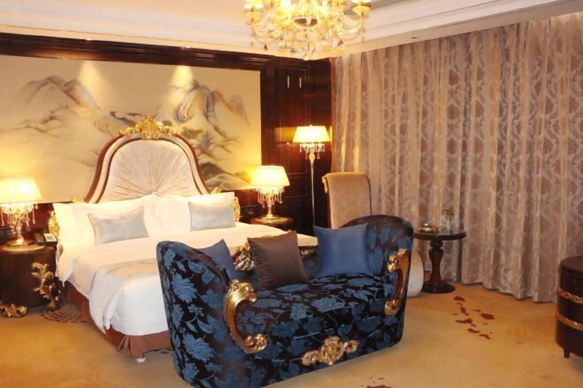 A luxurious bedroom with a large bed, ornate headboard, and a decorative chair.