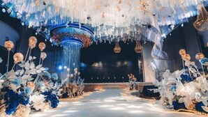 An indoor venue with a central stage, surrounded by floral arrangements and hanging decorations. - Hanxin International Hotel (Panjin)