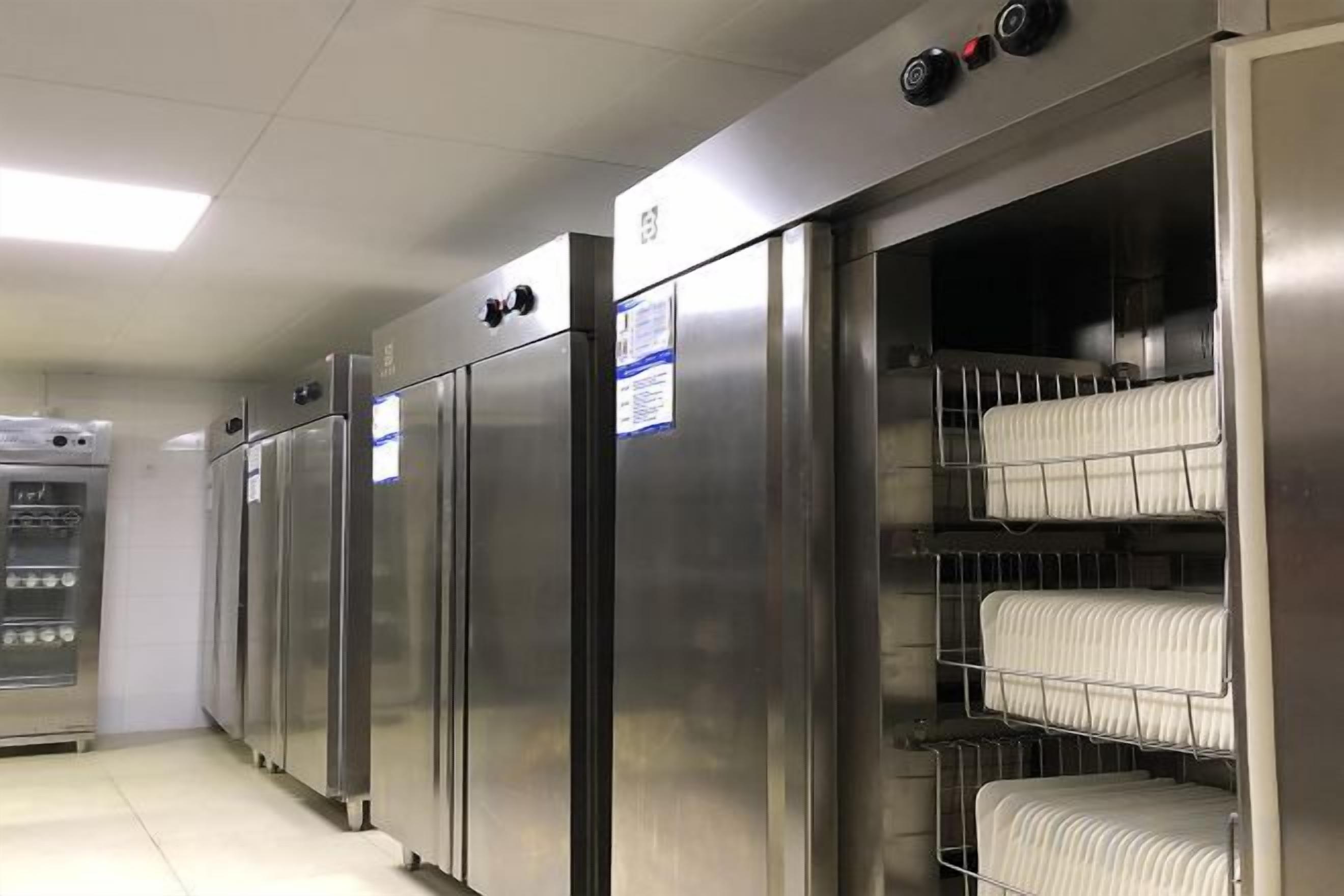 Una hilera de refrigeradores de acero inoxidable con estantes en su interior, probablemente para almacenar alimentos.