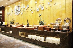 Una mesa de buffet con diferentes alimentos y una pared decorativa.
