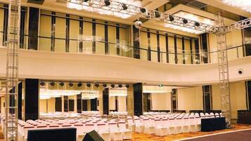 A large indoor venue with tiered seating, stage lighting, and a balcony.