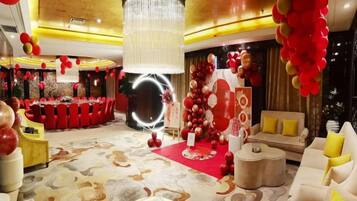 A hotel lobby with a round table, a chandelier, and red and gold decorations.