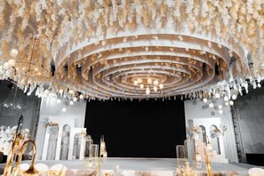 A stage with a circular design, chandeliers, and floral decorations. - Hanxin International Hotel (Panjin)
