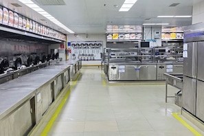 A clean, well-organized kitchen with stainless steel appliances, a long counter, and a variety of utensils and cookware. - Hanxin International Hotel (Panjin)