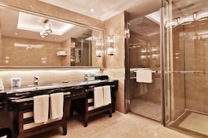A modern bathroom with a large mirror, dark vanity, two towels, a glass shower enclosure, and a marble floor. - Hanxin International Hotel (Panjin)