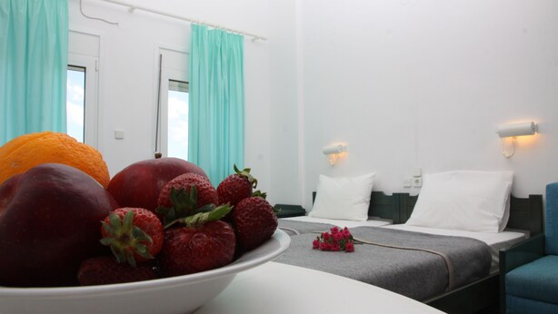 A hotel room with a bed, a bedside table with a bowl of fruit, and a window with curtains. - La Palma II (Malevizi)