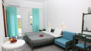 A bedroom with two beds, a desk, a chair, a small table with fruit, and a window with curtains. - La Palma II (Malevizi)
