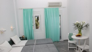 A hotel room with two beds, a small table with a fruit bowl, a potted plant, and a window with curtains. - La Palma II (Malevizi)