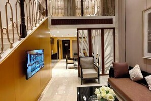 Relax in the hotel lobby, featuring a seating area with a sofa and chairs, a flat-screen TV, and decorative panels.