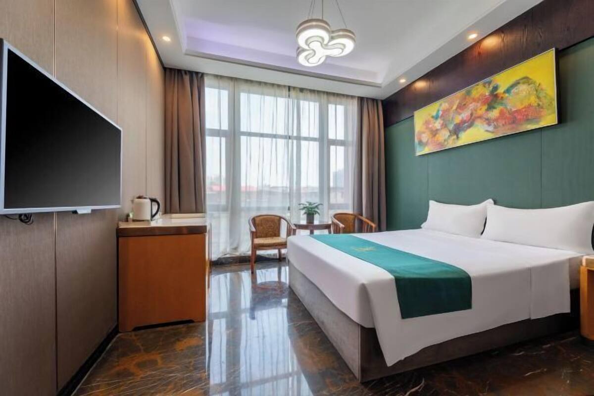 A hotel room with a bed, a desk, a chair, a television, and a window with curtains.