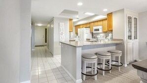A modern kitchen with a central island, wooden cabinets, and a microwave.