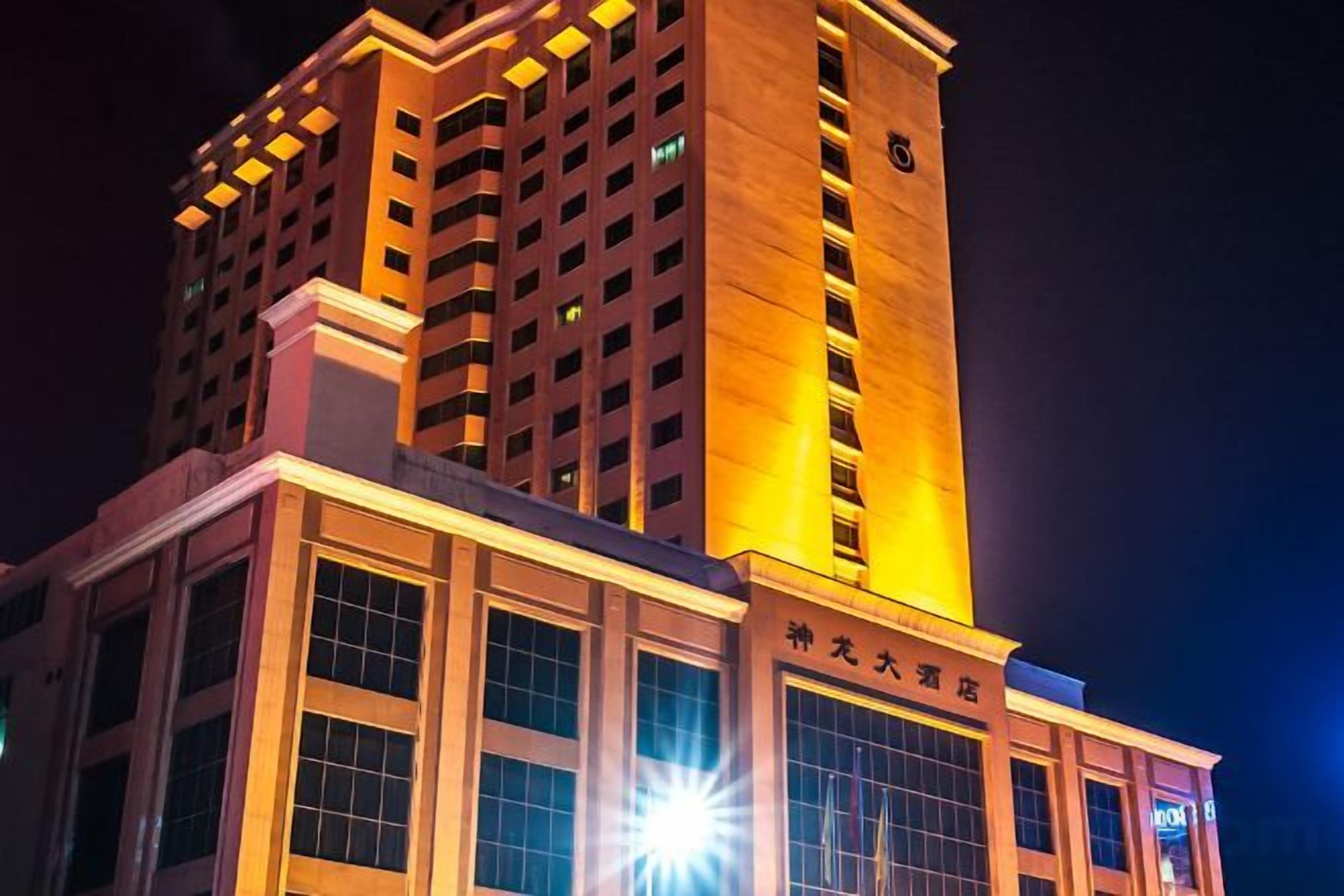 Un immeuble de grande hauteur, avec des fenêtres illuminées et un élément vertical marquant sur le côté droit.