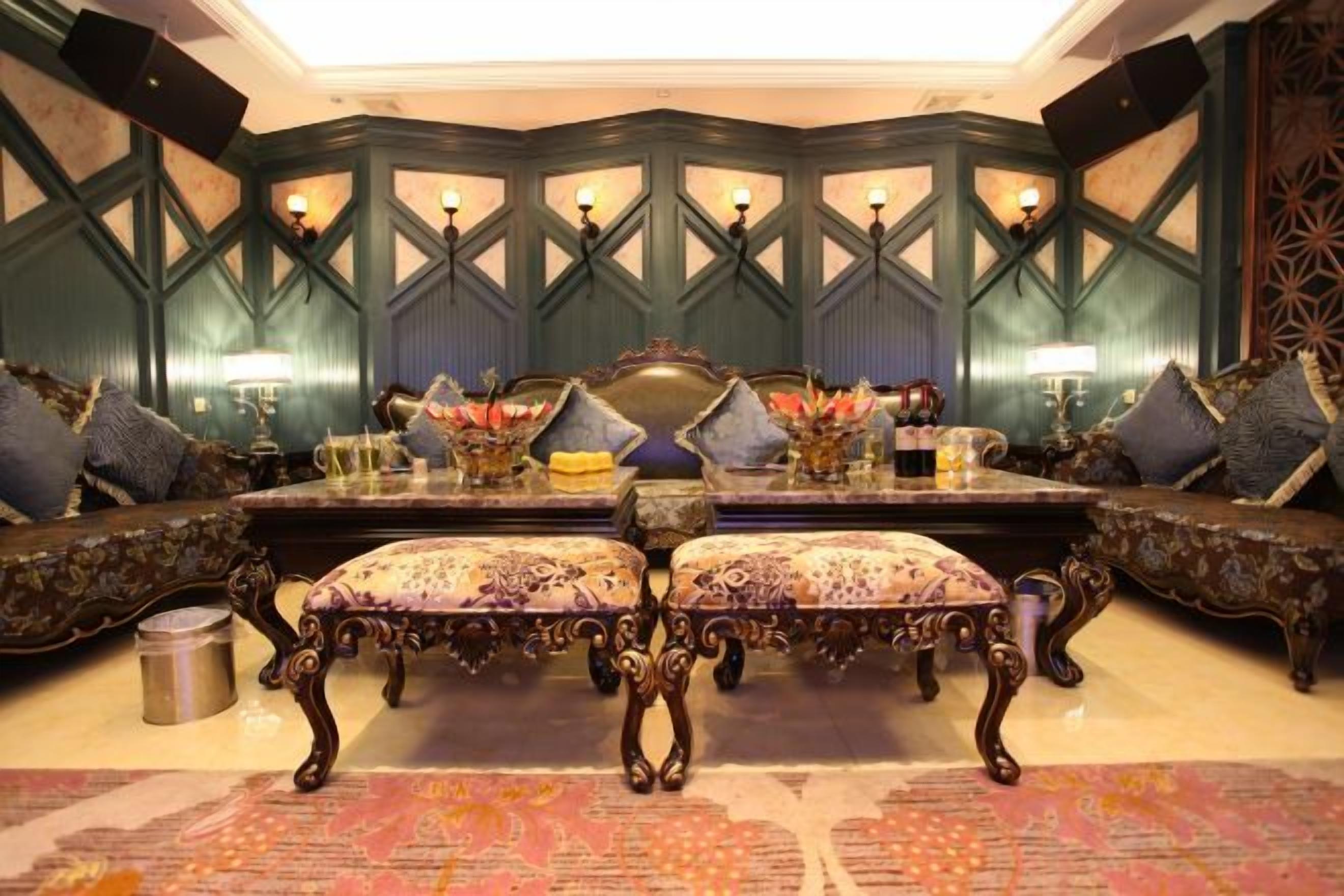 A room with a large ornate table, upholstered chairs, and a patterned rug.
