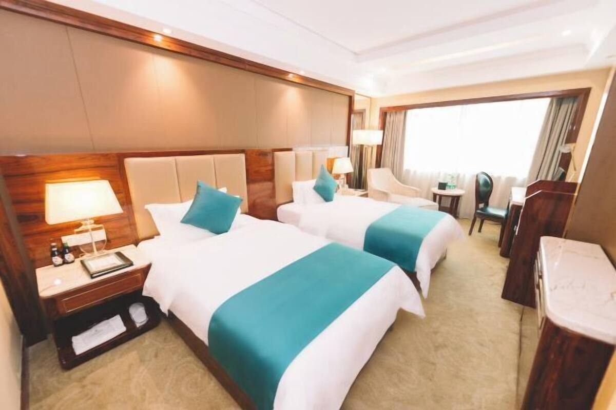 Ein Hotelzimmer mit zwei Betten, einem Schreibtisch, einem Stuhl und einem kleinen Tisch.