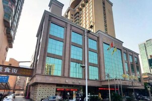 Un edificio de varios pisos con amplios ventanales y un letrero que indica un hotel.