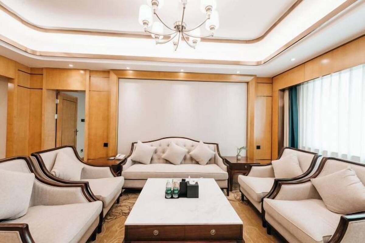 Ein Hotelzimmer mit einer Couch, zwei Sesseln, einem Couchtisch und einer Deckenleuchte.