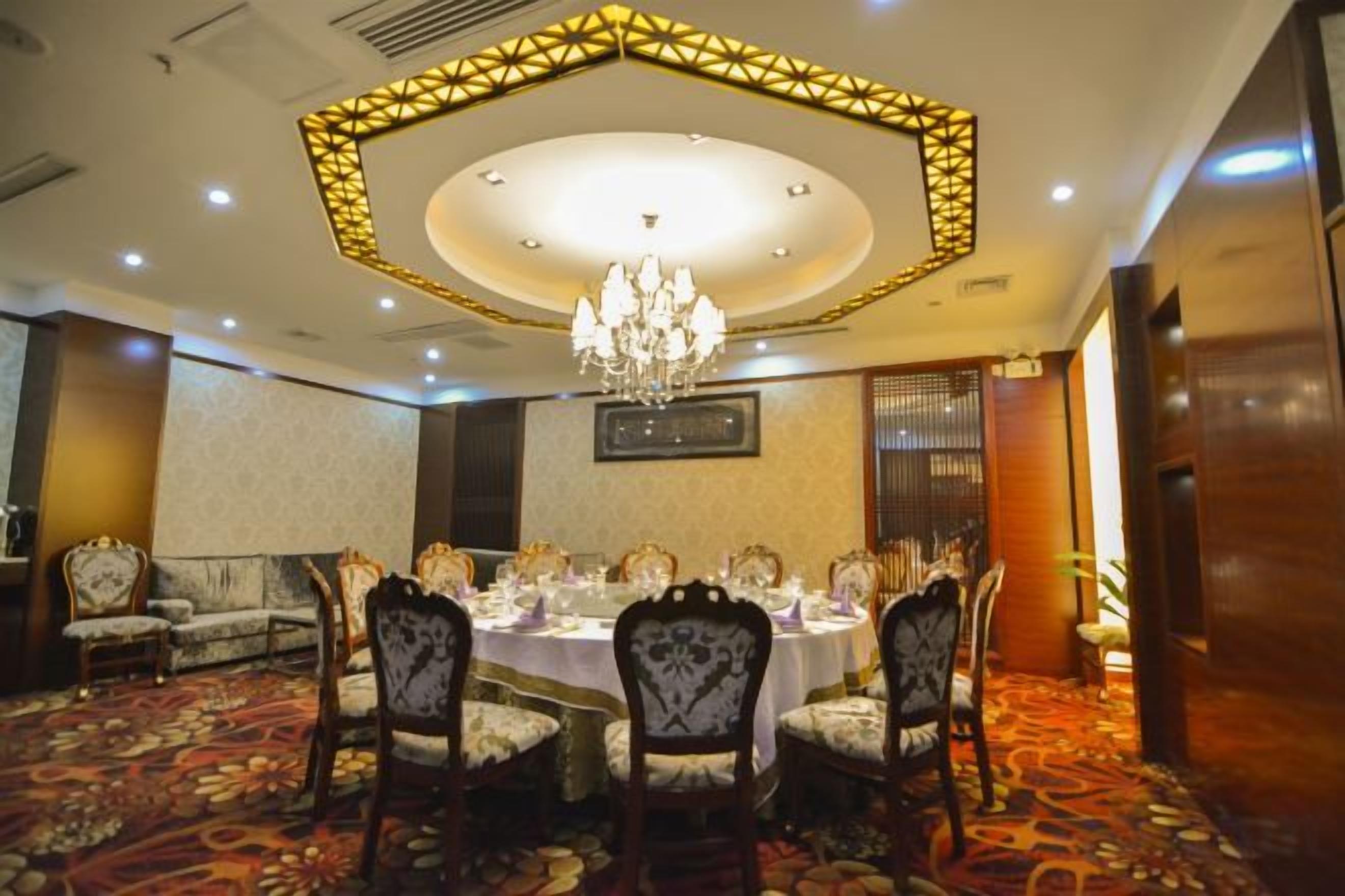 A conference room with a round table, chairs, and a chandelier.