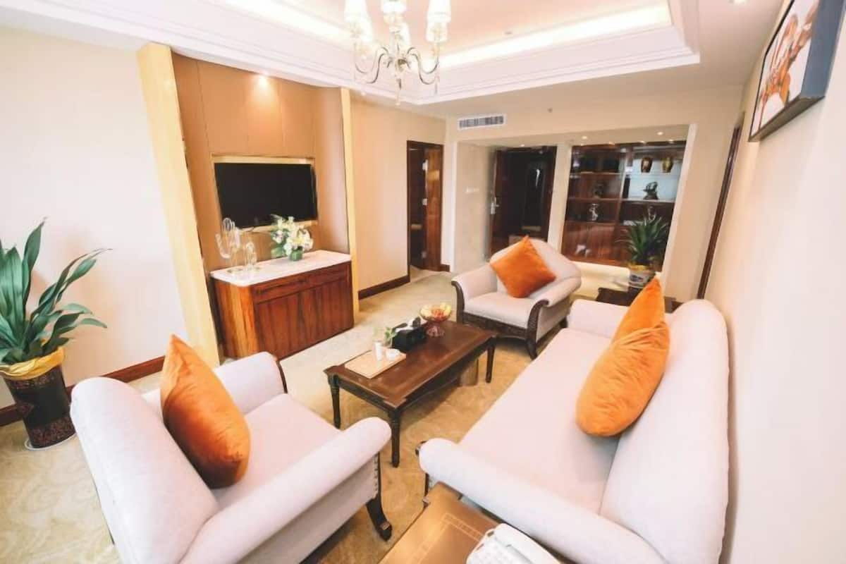 Eine Hotelhalle mit einer Sofagarnitur, einem Couchtisch, einem Fernseher und einer Rezeption.