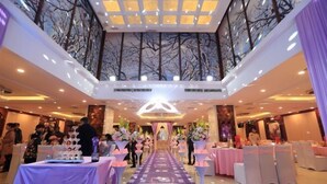 A spacious hall with a central aisle, tables with pink tablecloths, and floral centerpieces. - Shen Long Hotel (Hengyang)