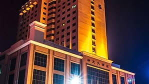 A high-rise building with illuminated windows and a sign indicating it is a hotel. - Shen Long Hotel (Hengyang)