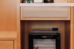 Un minibar con un electrodoméstico negro etiquetado como "migu" en un mueble de madera.