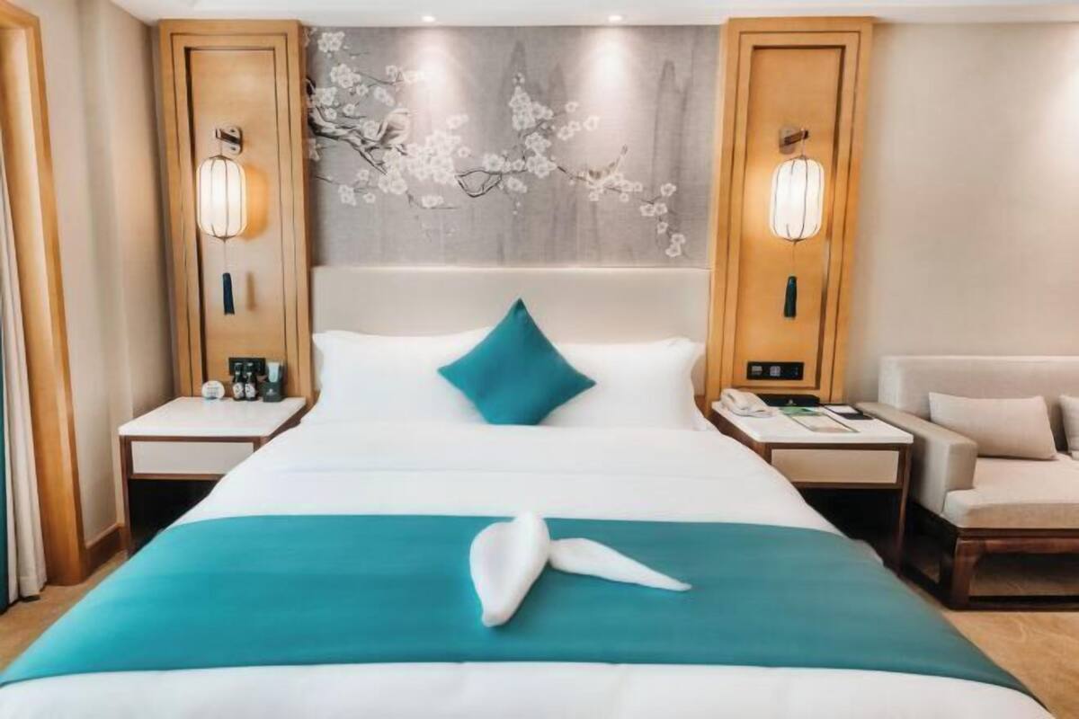 Ein Hotelzimmer mit einem Bett, zwei Nachttischen, einem Sessel und einer Wand mit floralem Wandbild.