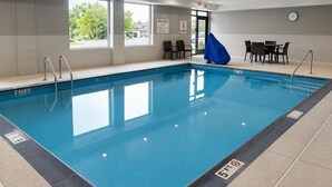 Ein klares Hallenbad mit Tiefenmarkierung von 1,5 Metern, Hinweisschild mit Poolregeln und einer Uhr an der Wand.