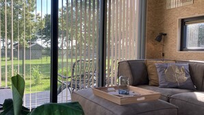 Un salon moderne avec une grande fenêtre, un canapé, une table basse avec un plateau et une plante en pot.