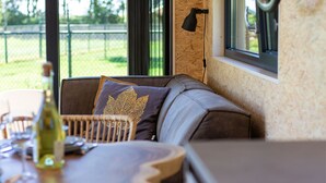 Un coin salon confortable avec un banc rembourré, une table sur laquelle se trouve une bouteille et une lampe.