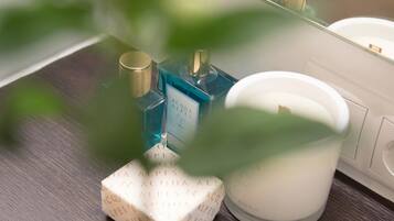 A bathroom counter with a white candle, two blue bottles, and a white box with text.