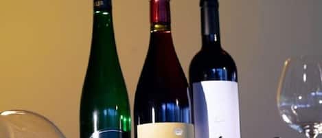 Three wine bottles and a glass of wine on a table.
