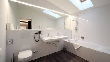 Un baño moderno con tragaluz, un lavabo blanco, inodoro y bañera.