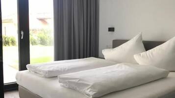 A modern hotel room with a large bed, grey curtains, and a view of the outdoors.