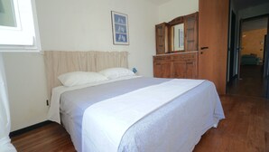 A bedroom with a bed, a wooden wardrobe, a mirror, and a framed picture on the wall. - Apartment An in panoramic villa (San Salvatore)