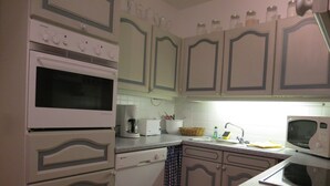 A kitchen with white cabinetry, a microwave, a toaster, and a sink. - Large three-room apartment with 2 bathrooms for a maximum of 8 people (Kellenhusen)