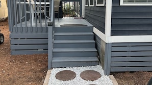 Uma casa com varanda coberta, um pequeno espaço de estar ao ar livre e uma entrada de garagem.