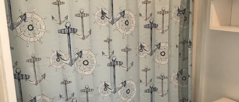A bathroom with a nautical-themed shower curtain, a white sink, and a toilet.