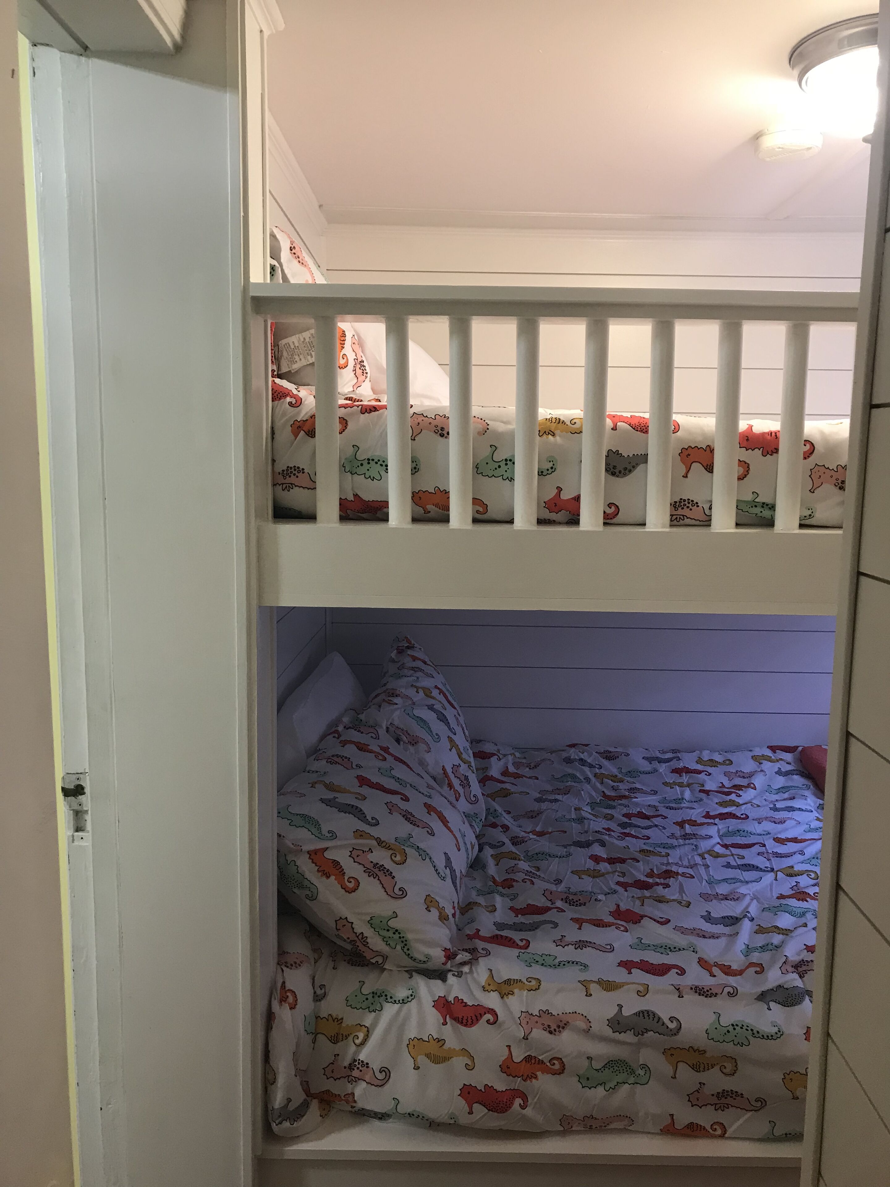A bunk bed with a white frame and colorful bedding featuring animal prints.