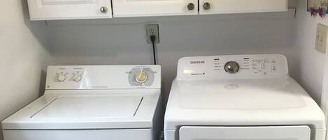 Ein Waschraum mit zwei weißen Frontlader-Waschmaschinen und einem weißen Schrank darüber.