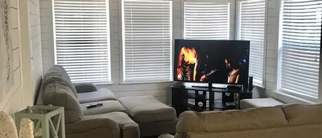 A living room with a television, two couches, a wooden coffee table, and a ceiling fan.