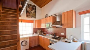 Una cocina con armarios de madera, lavadora, estufa y una ventana.
