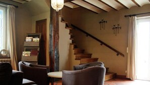 Un salon avec une cheminée, un escalier et une bibliothèque.